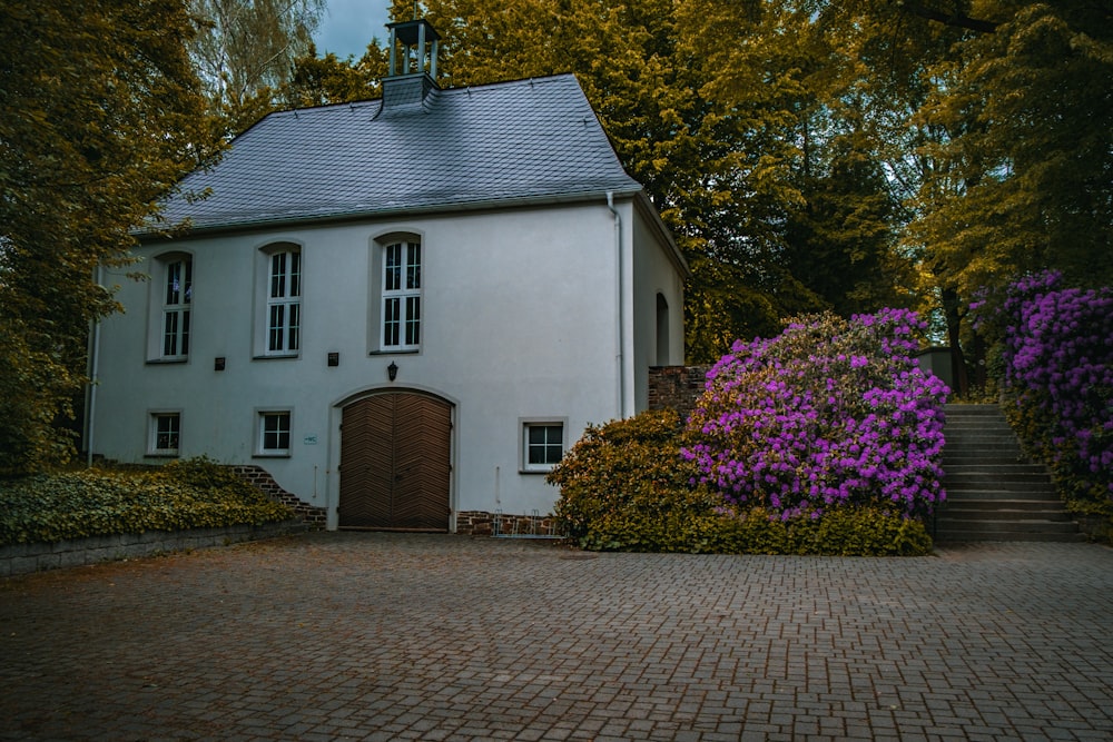 a white house with purple flowers in front of it