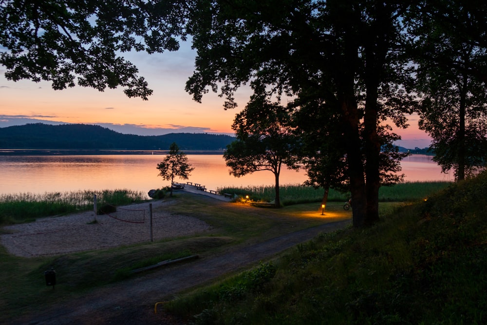 a sunset view of a lake with a boat on the shore