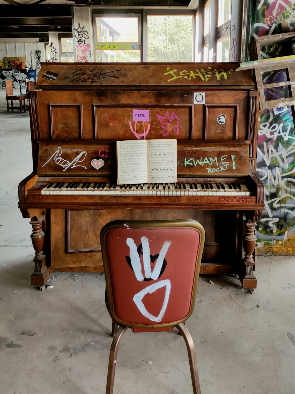 a piano with graffiti on it and a book on top of it
