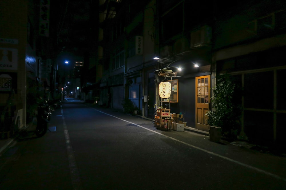 a dark street at night with a clock on the wall