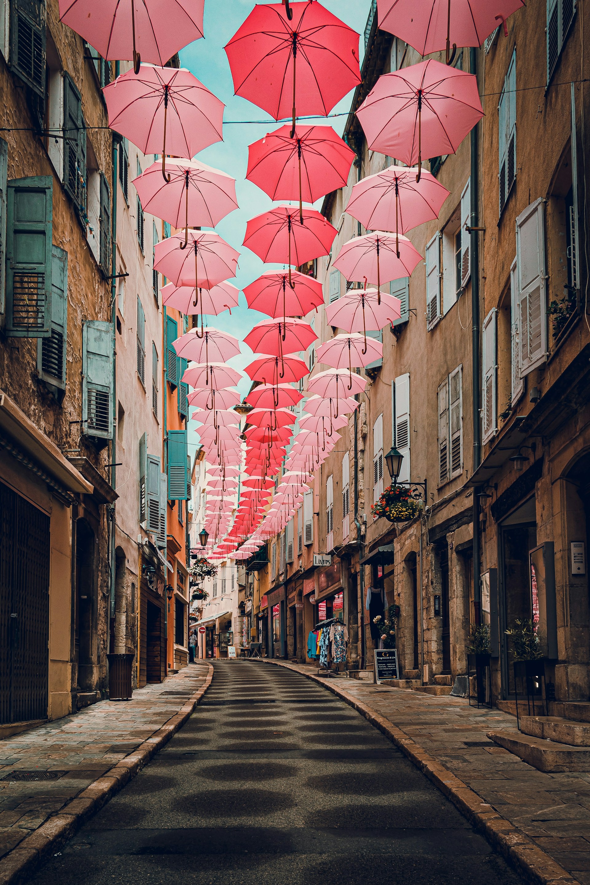 a street lined with pink umbrellas hanging from the ceiling