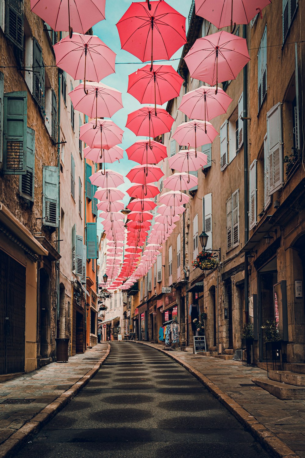 a street lined with pink umbrellas hanging from the ceiling