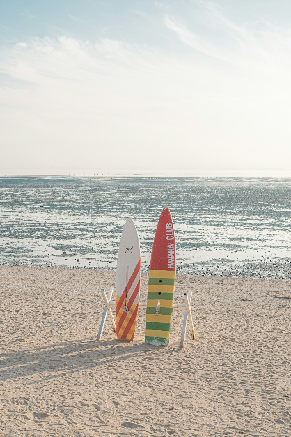 a couple of surfboards sitting on top of a sandy beach