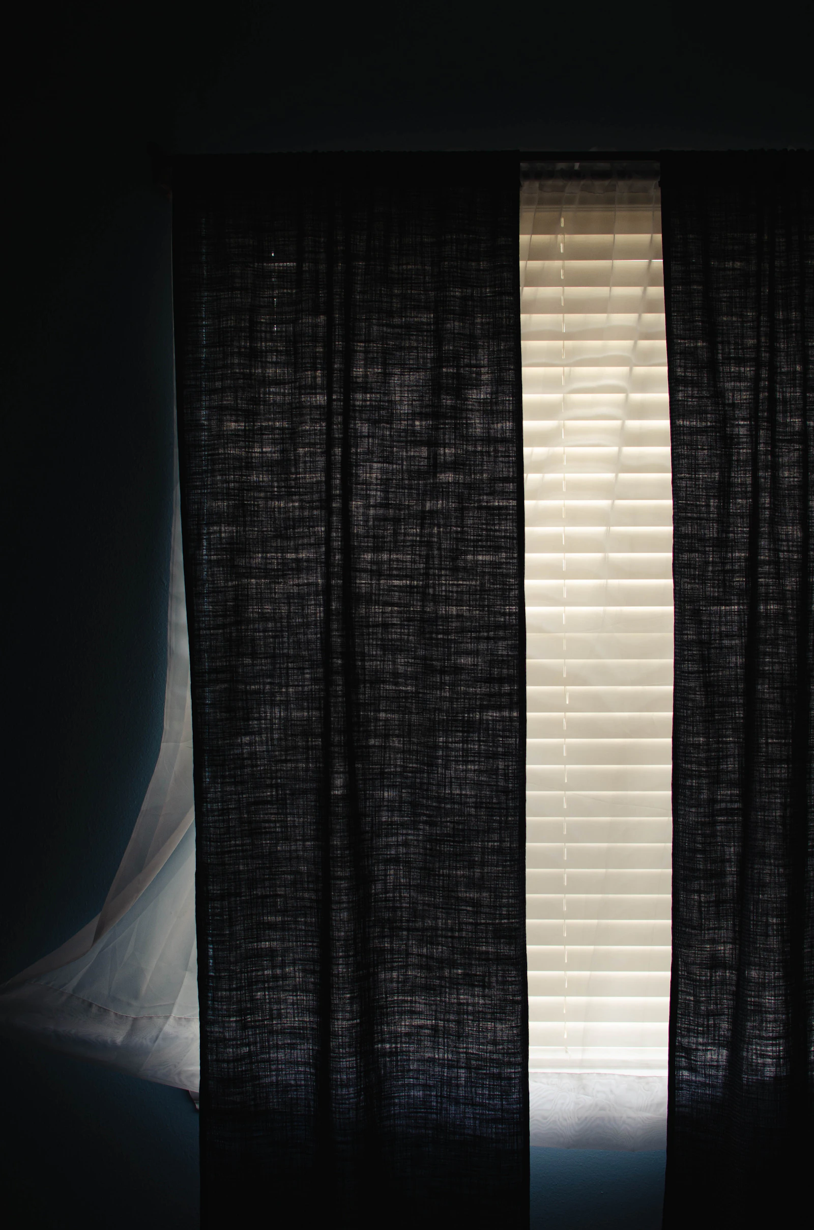 A window with a black curtain and a white curtain