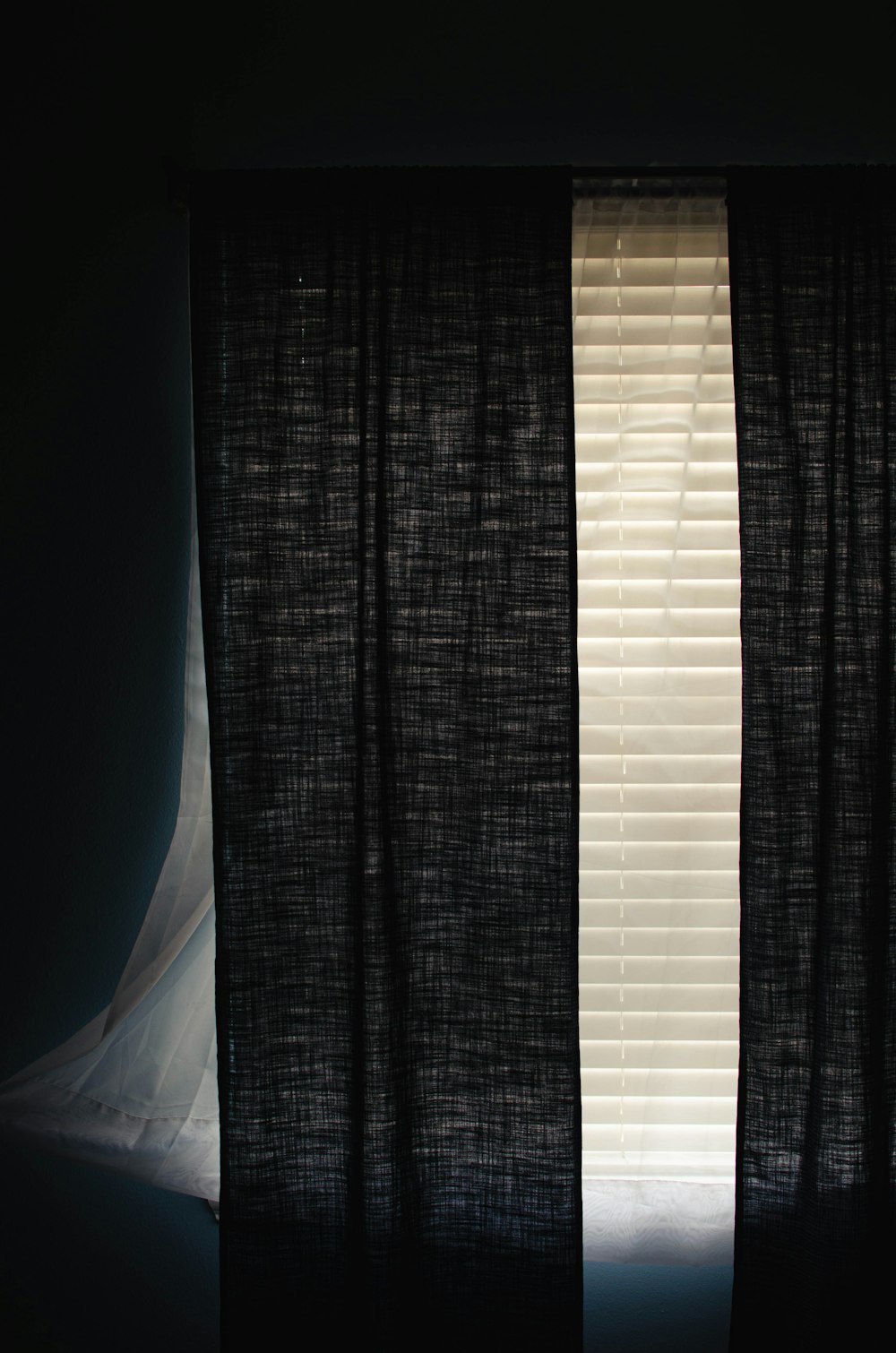 a window with a black curtain and a white curtain