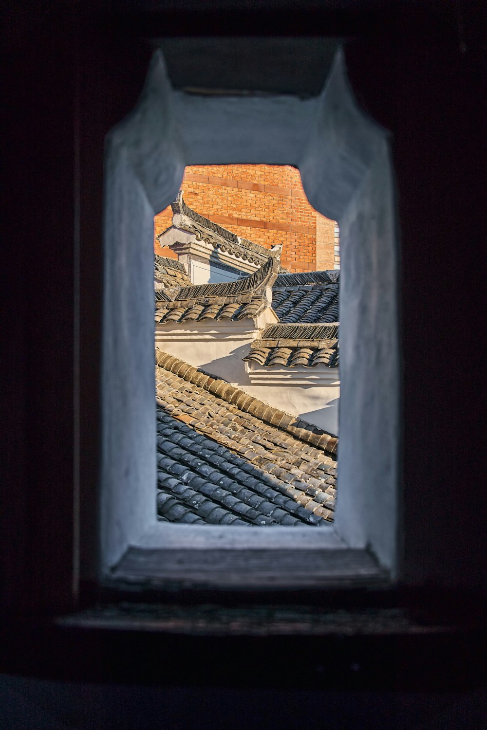 a window with a view of a roof and a building