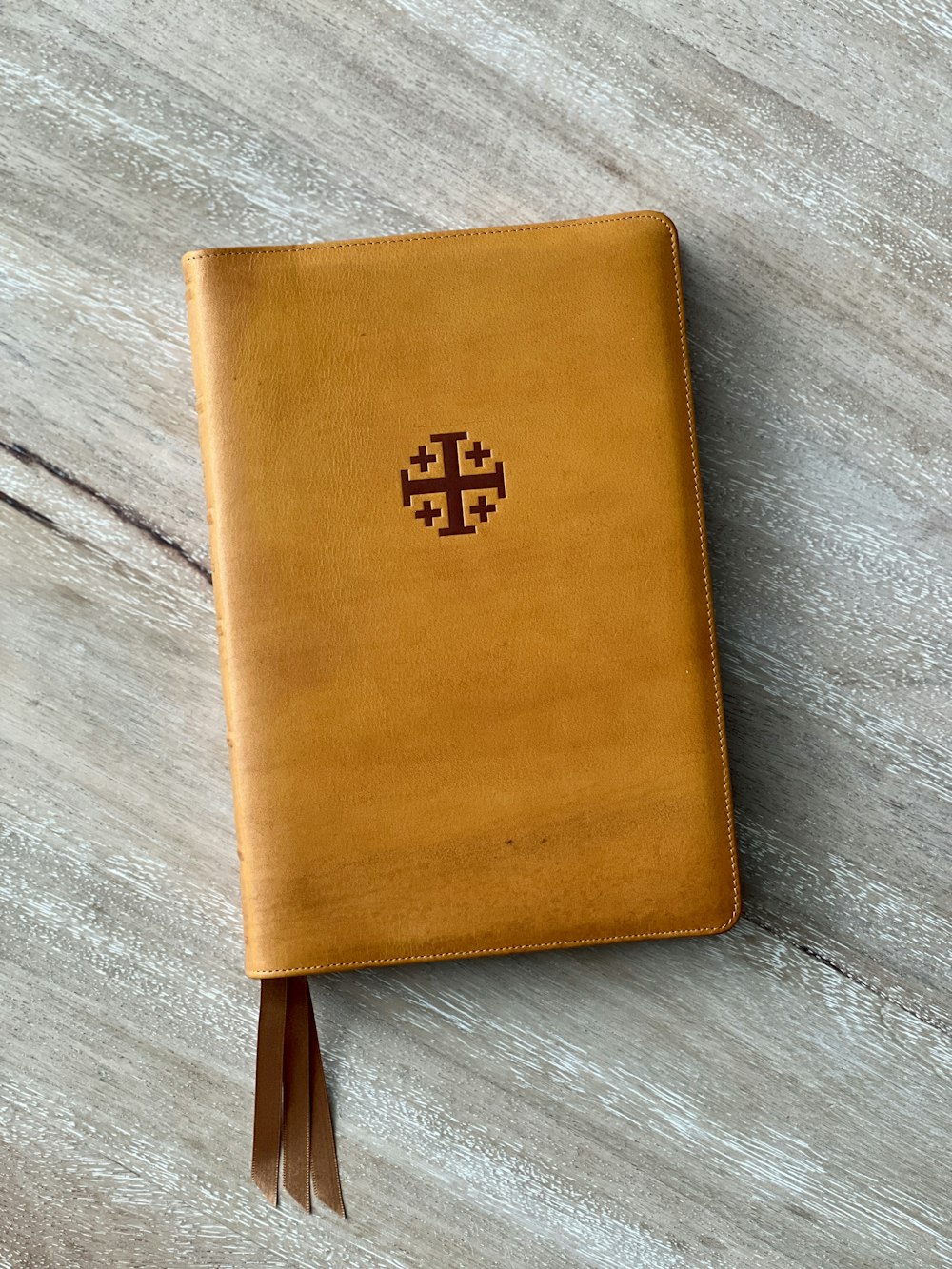 a brown leather journal with a cross on it