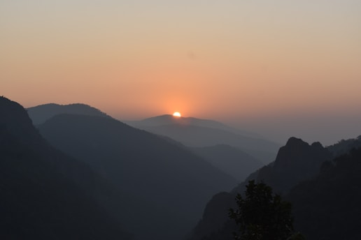 the sun is setting over the mountains in the distance