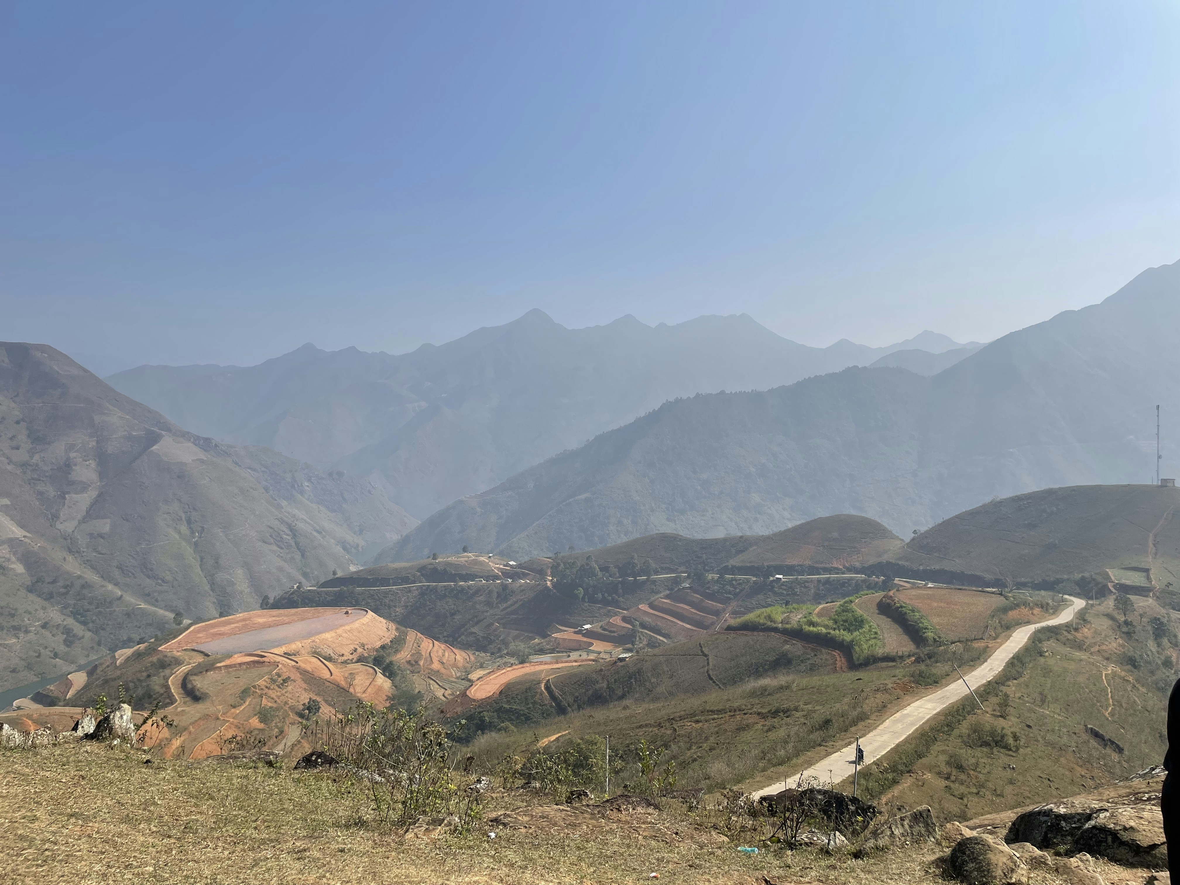 a man standing on top of a hill next to a lush green hillside