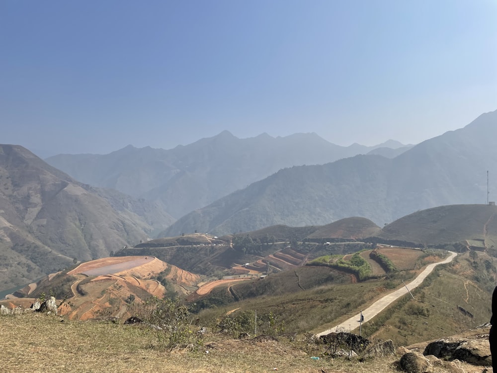 a man standing on top of a hill next to a lush green hillside