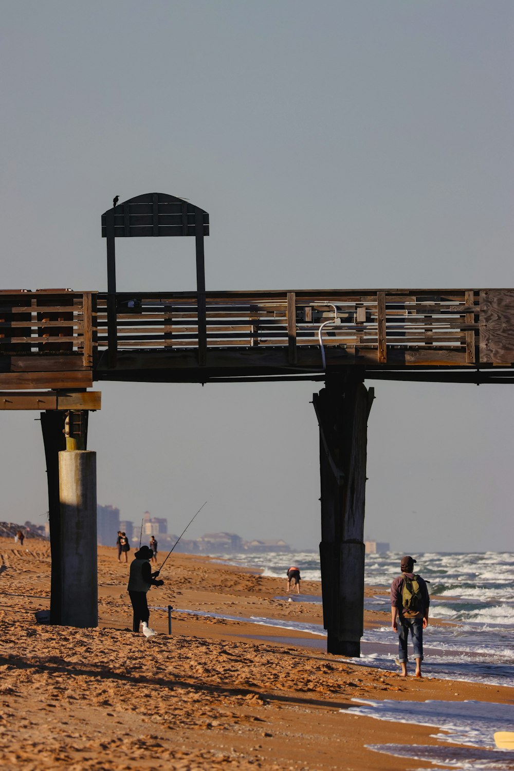 a couple of people walking on a beach next to the ocean