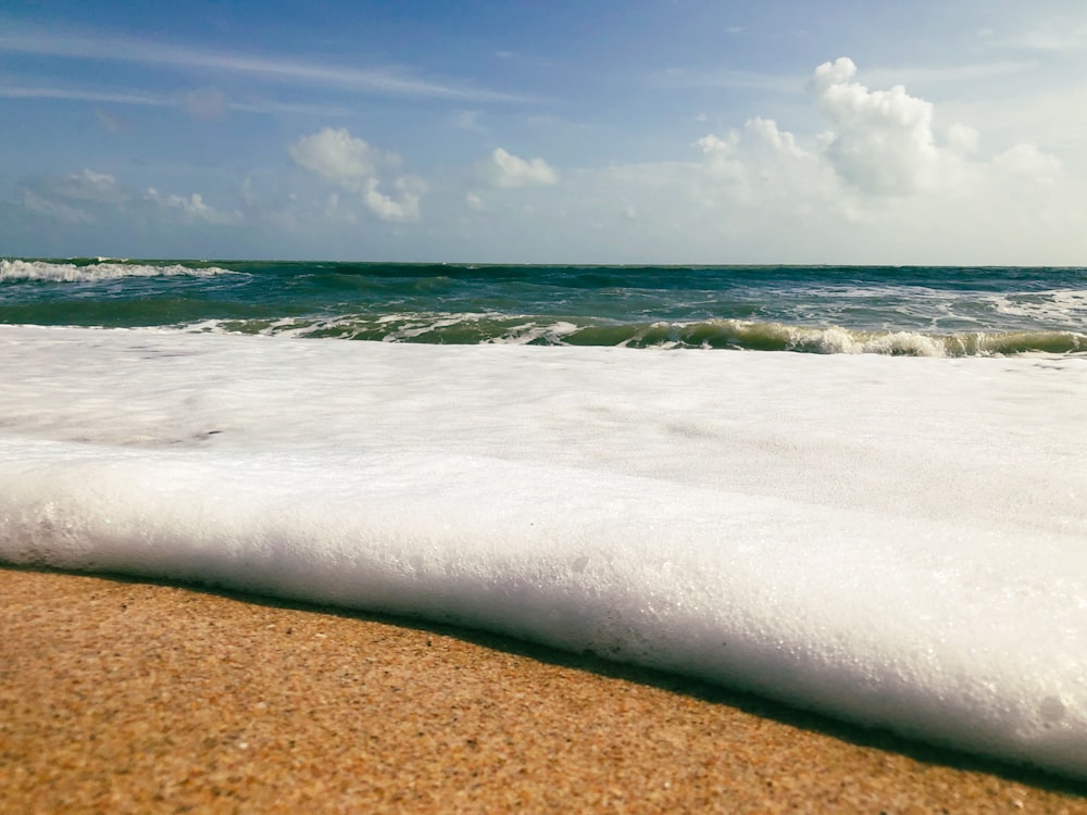 a wave rolls in on a sandy beach