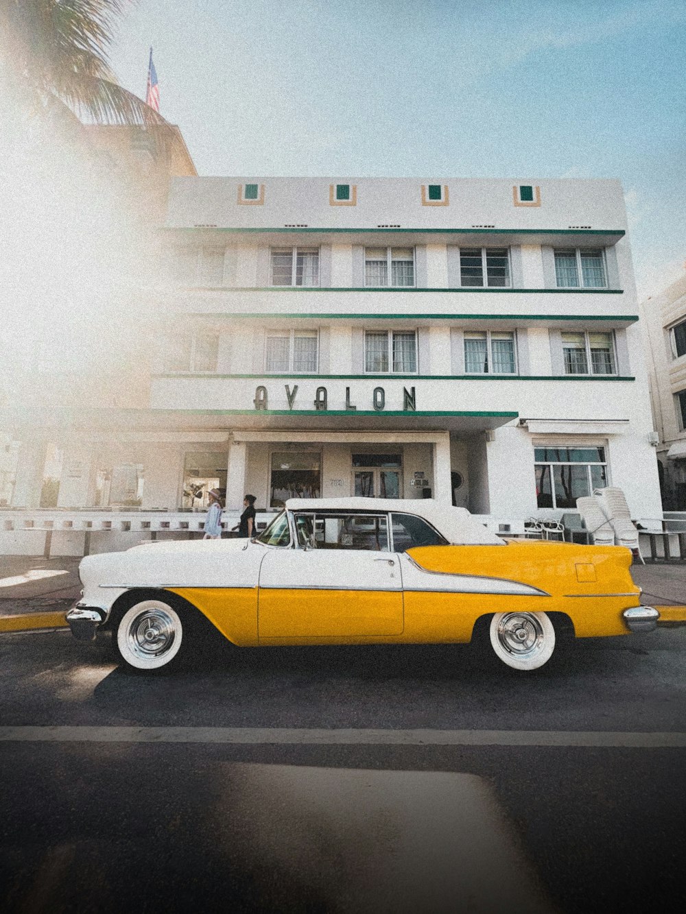 a yellow and white car parked in front of a hotel