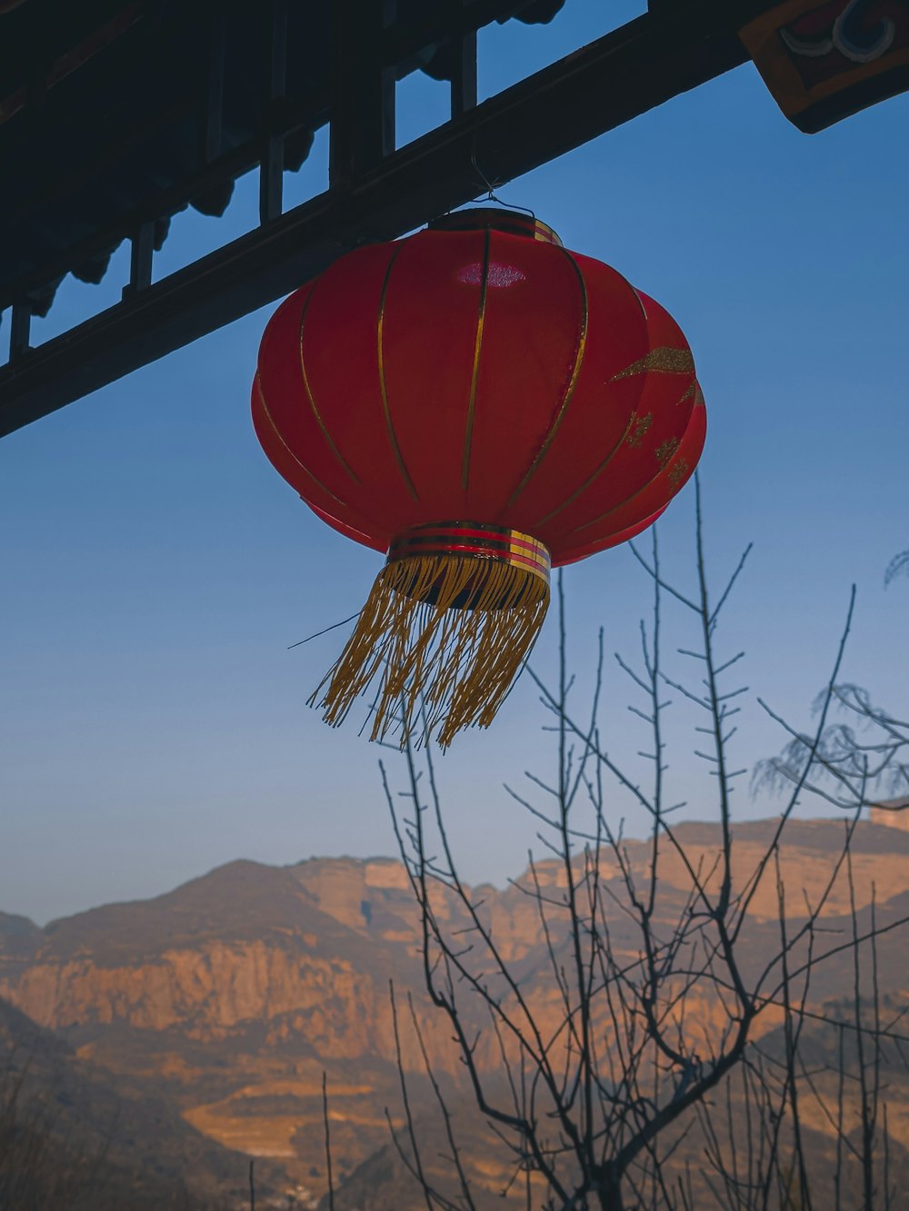 two red paper lanterns hanging from a roof