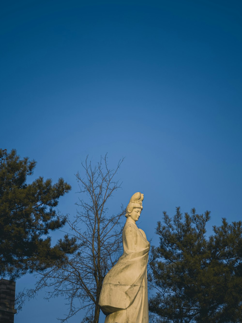 Una estatua de una persona con un árbol en el fondo