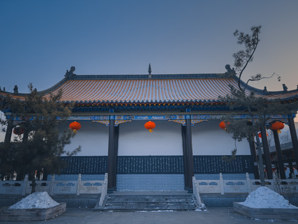 a chinese building with orange lanterns hanging from it's roof