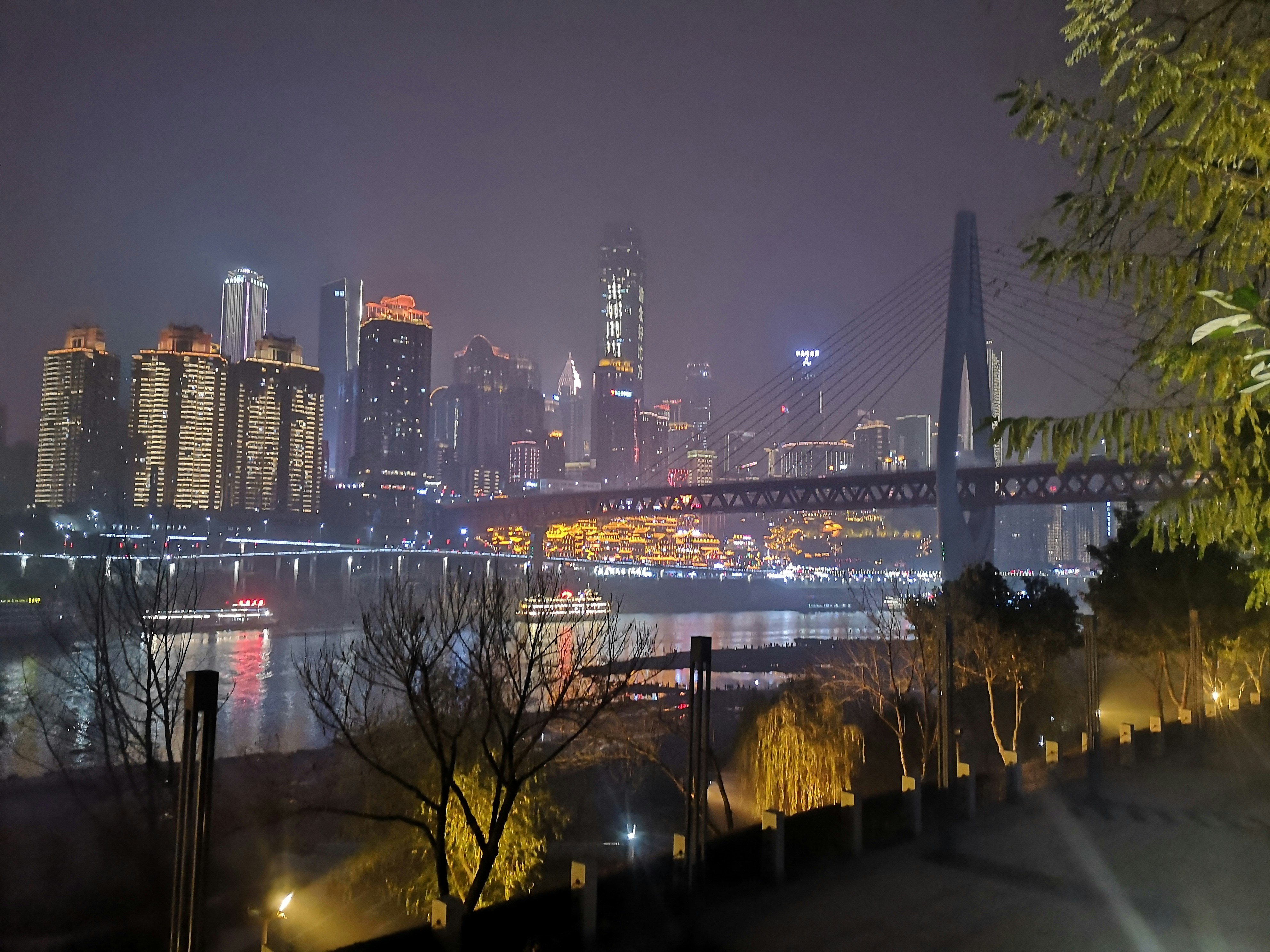 a view of a city at night with a bridge in the foreground