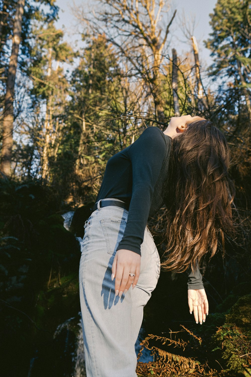 a woman with long hair standing in the woods