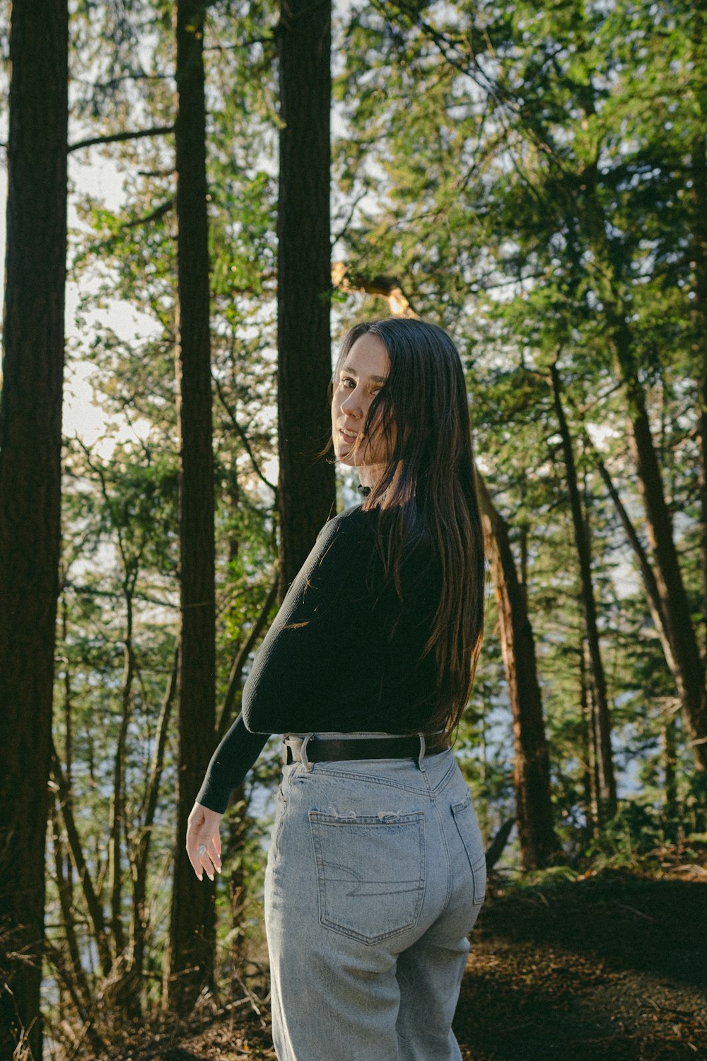 a woman standing in the woods with trees in the background