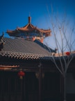Blue sky framing a traditional temple roof with red accents in the foreground.
