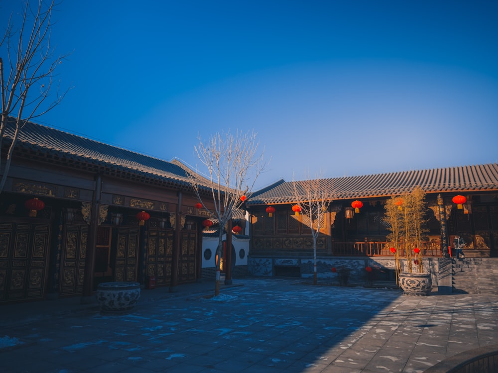 the courtyard of a chinese building with lanterns hanging from the roof