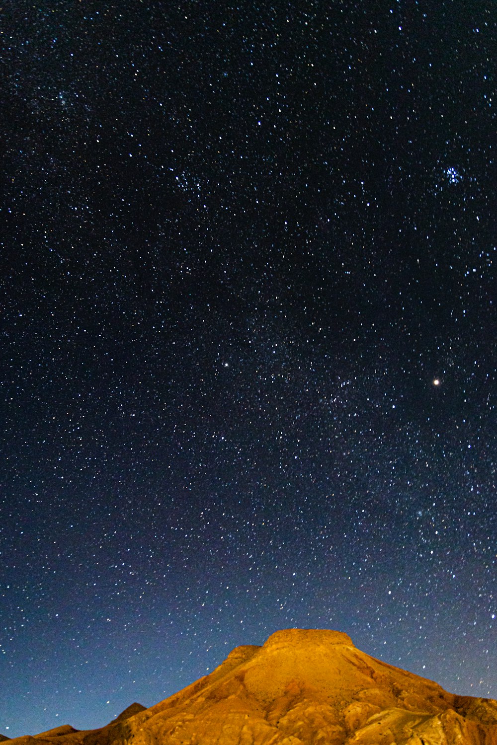 the night sky with stars above a mountain