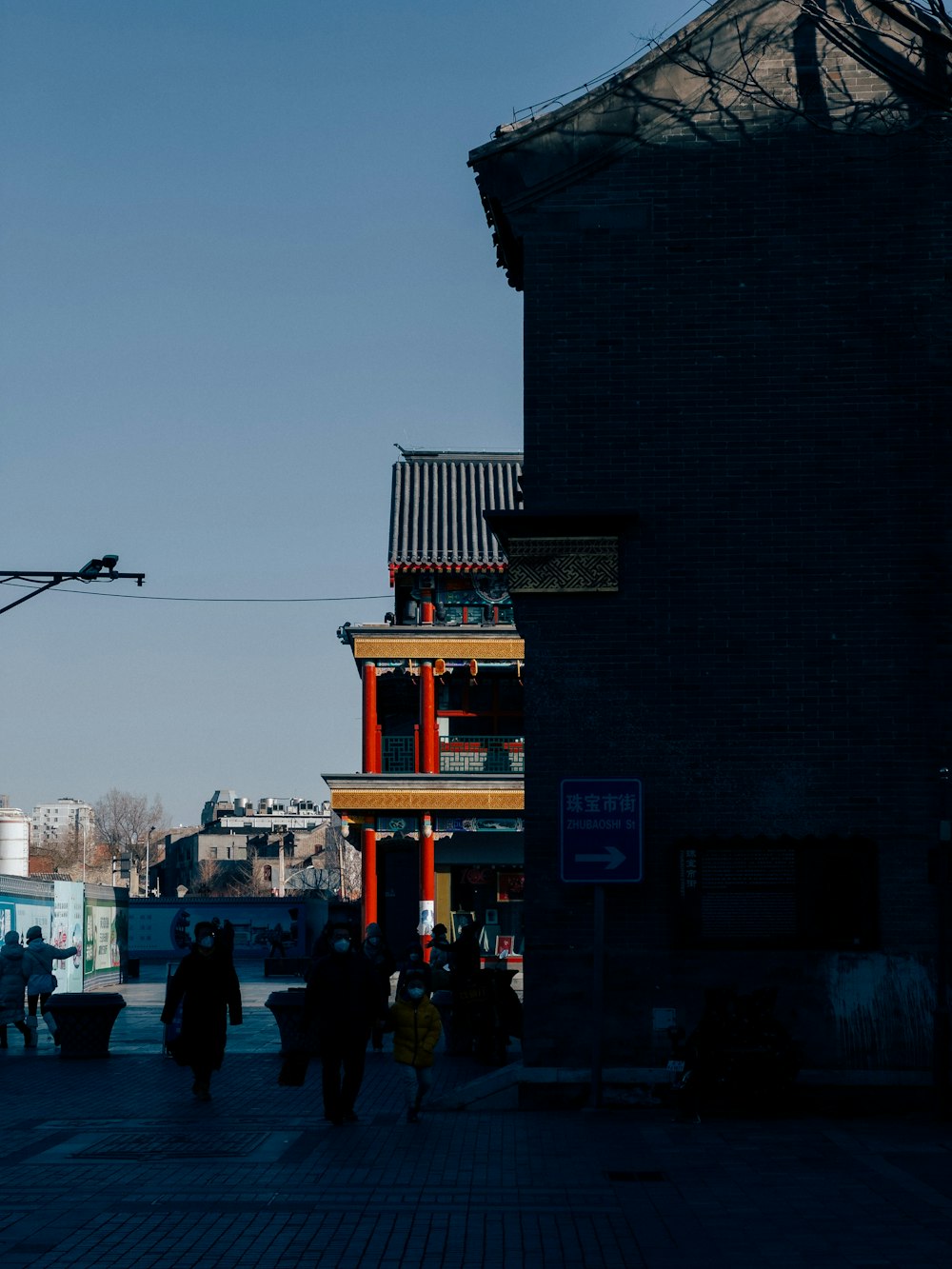 a group of people walking down a street next to tall buildings