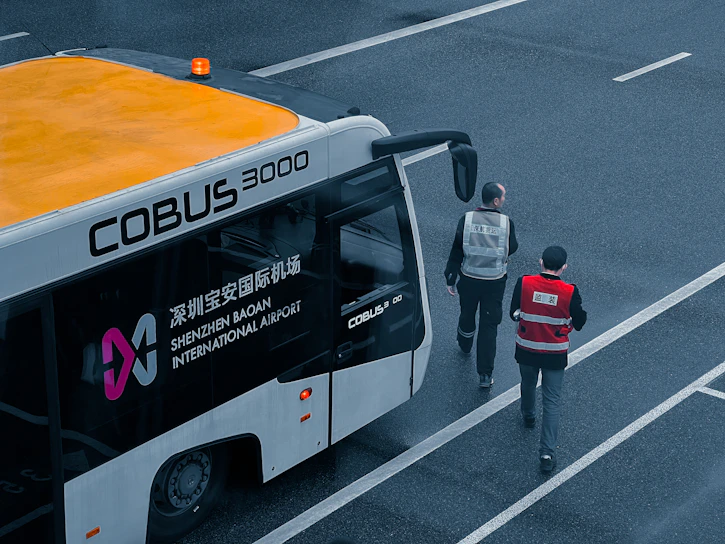 A sleek Nexus Liners bus parked at a bustling airport terminal, ready for a group transfer.