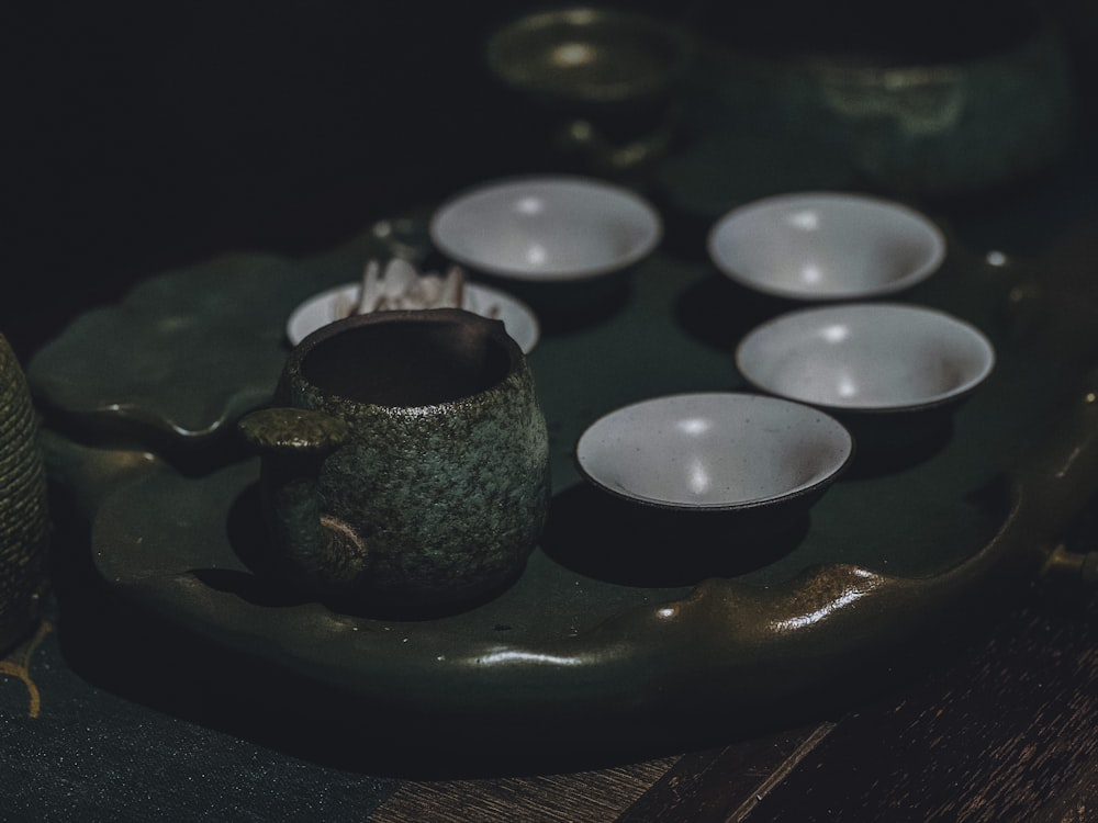a tray with a tea pot and five cups on it