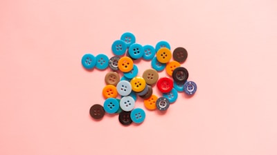 a pile of buttons sitting on top of a pink surface
