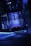 A dimly lit interior space with reflective walls and blue neon lights lining the edges. The ceiling features a projection with an abstract design. The overall atmosphere is futuristic, with metallic and glass textures.