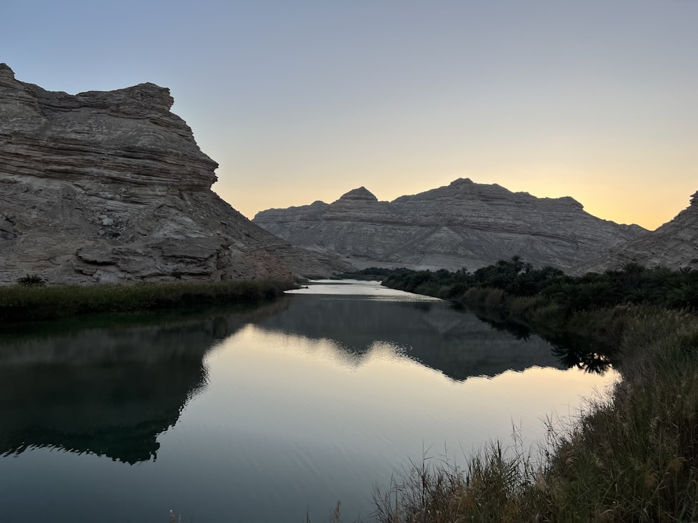 a body of water surrounded by mountains and grass