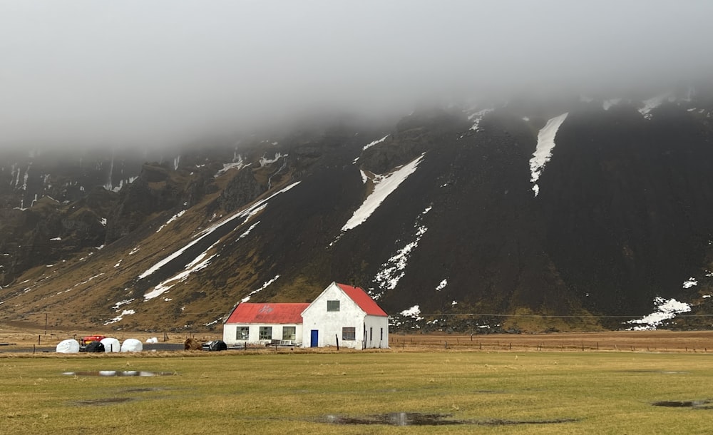 a white house with a red roof in front of a mountain