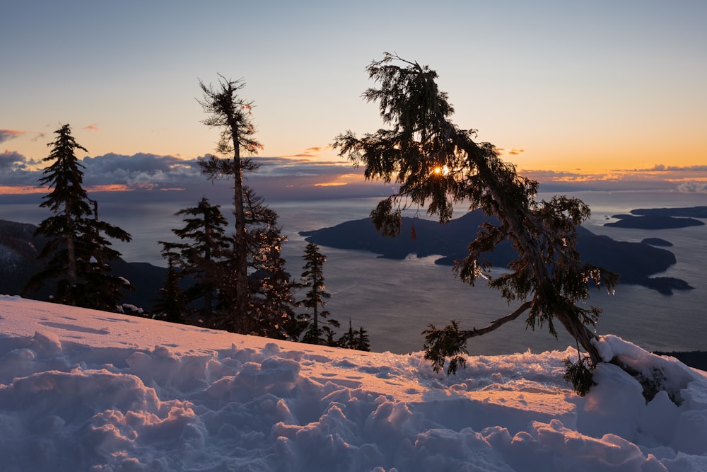 the sun is setting over a snowy mountain