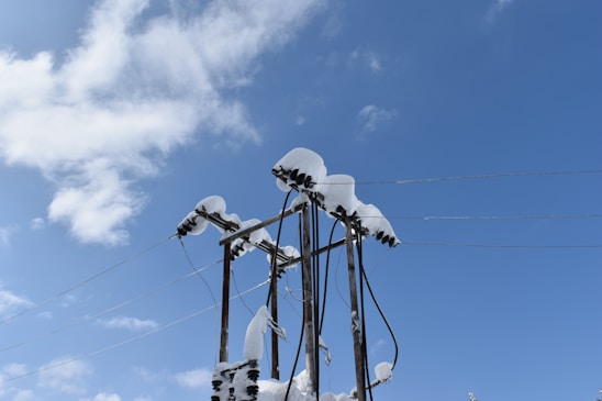 Technicians inspecting high-voltage power lines against a clear blue sky in a northeastern town.