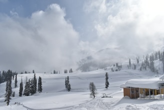 a snow covered mountain with a small cabin in the foreground