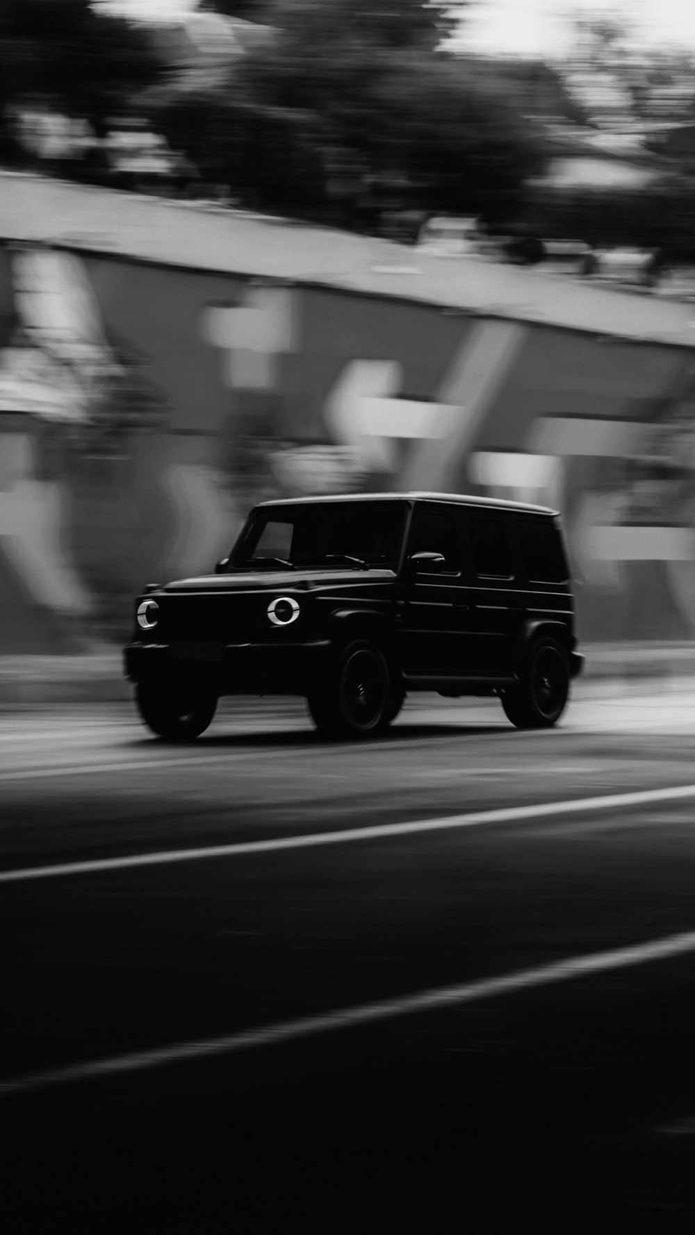 a black truck driving down a street next to a graffiti covered wall