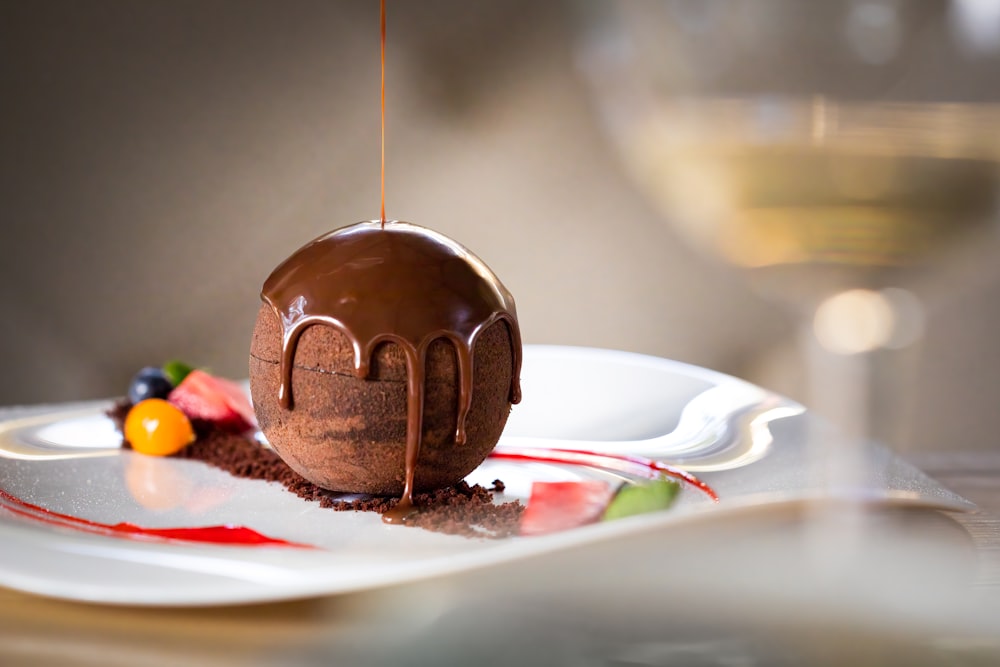 a chocolate dessert on a plate with a glass of wine in the background