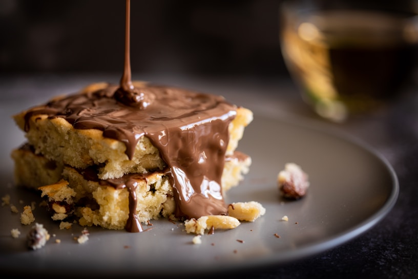 Close-up of a golden blondie with a drizzle of caramel on a rustic wooden board.