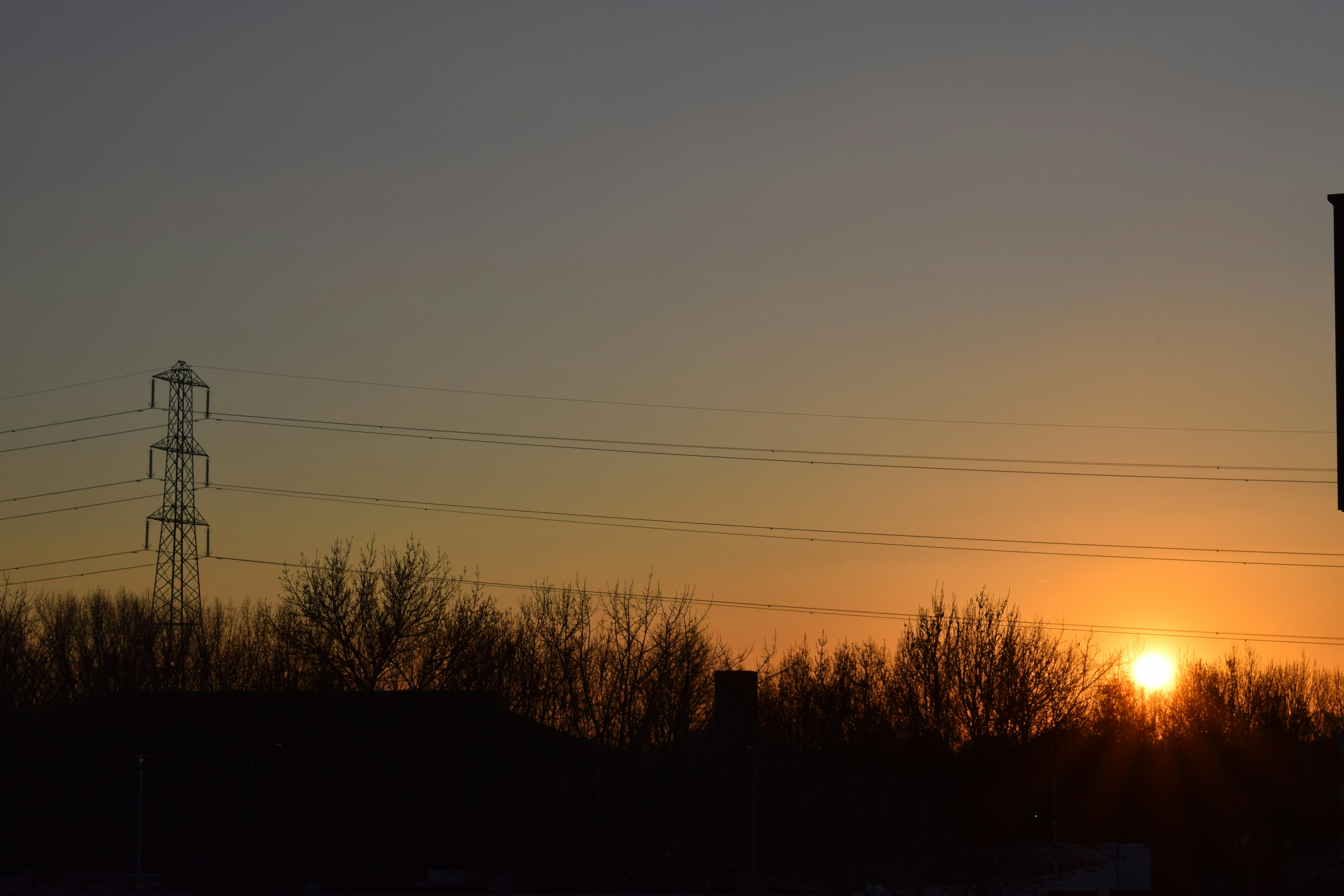 the sun is setting behind power lines and telephone poles