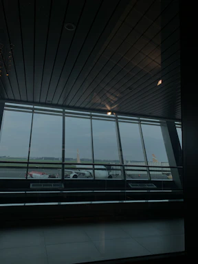 A sleek corporate office with a large window overlooking an airport runway bathed in soft morning light.