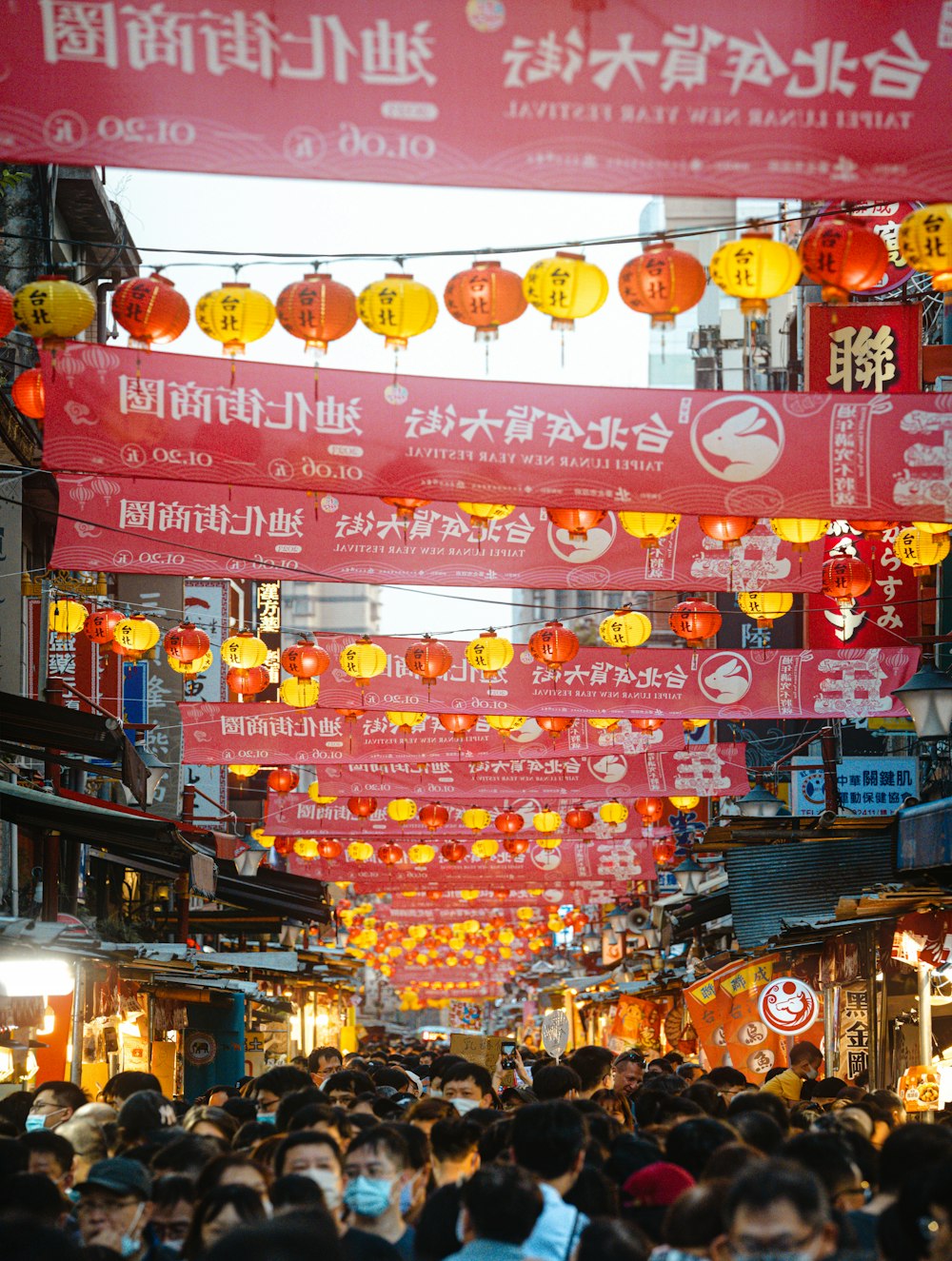 a crowd of people walking down a street under red banners