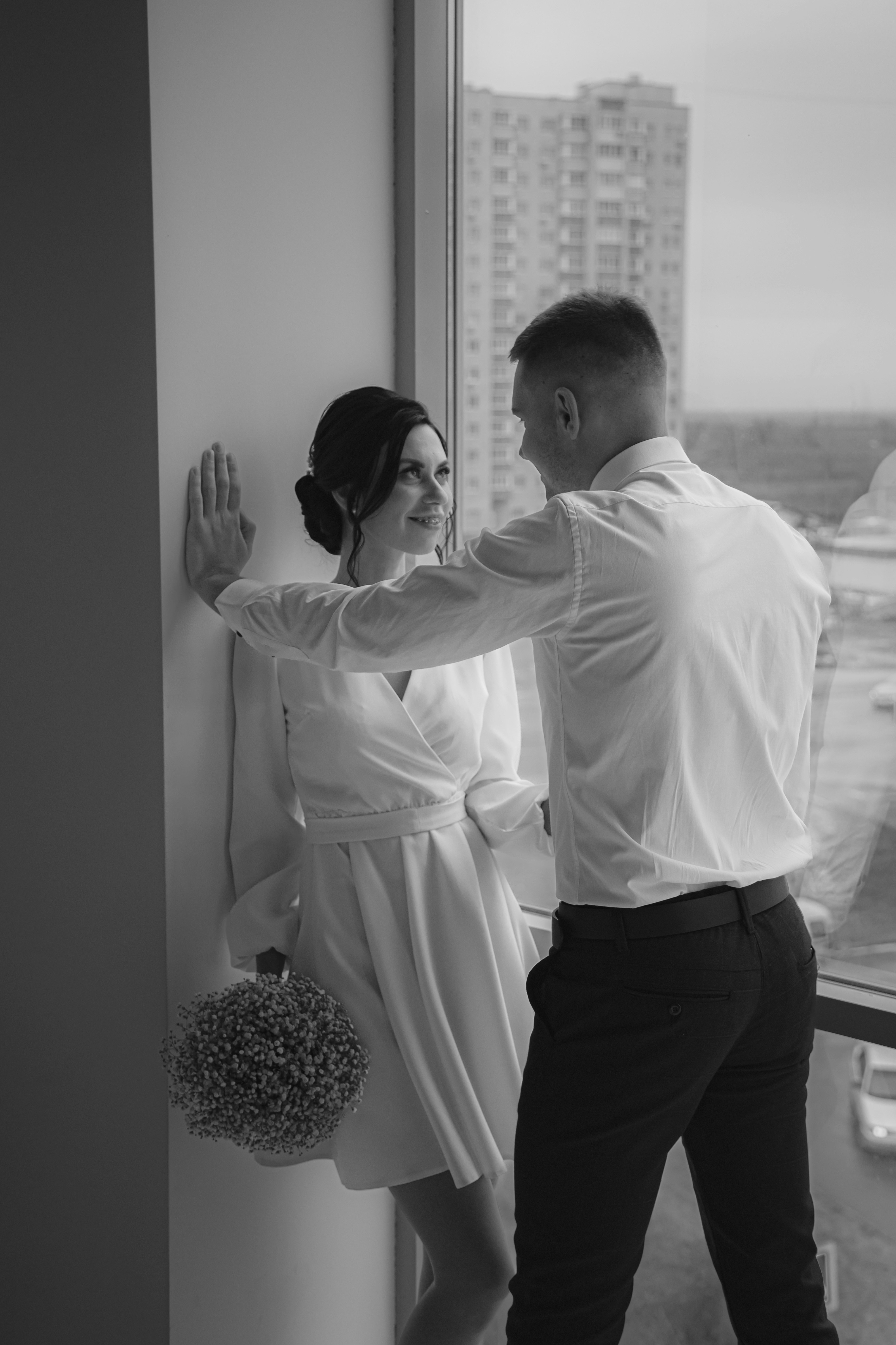 a man standing next to a woman near a window