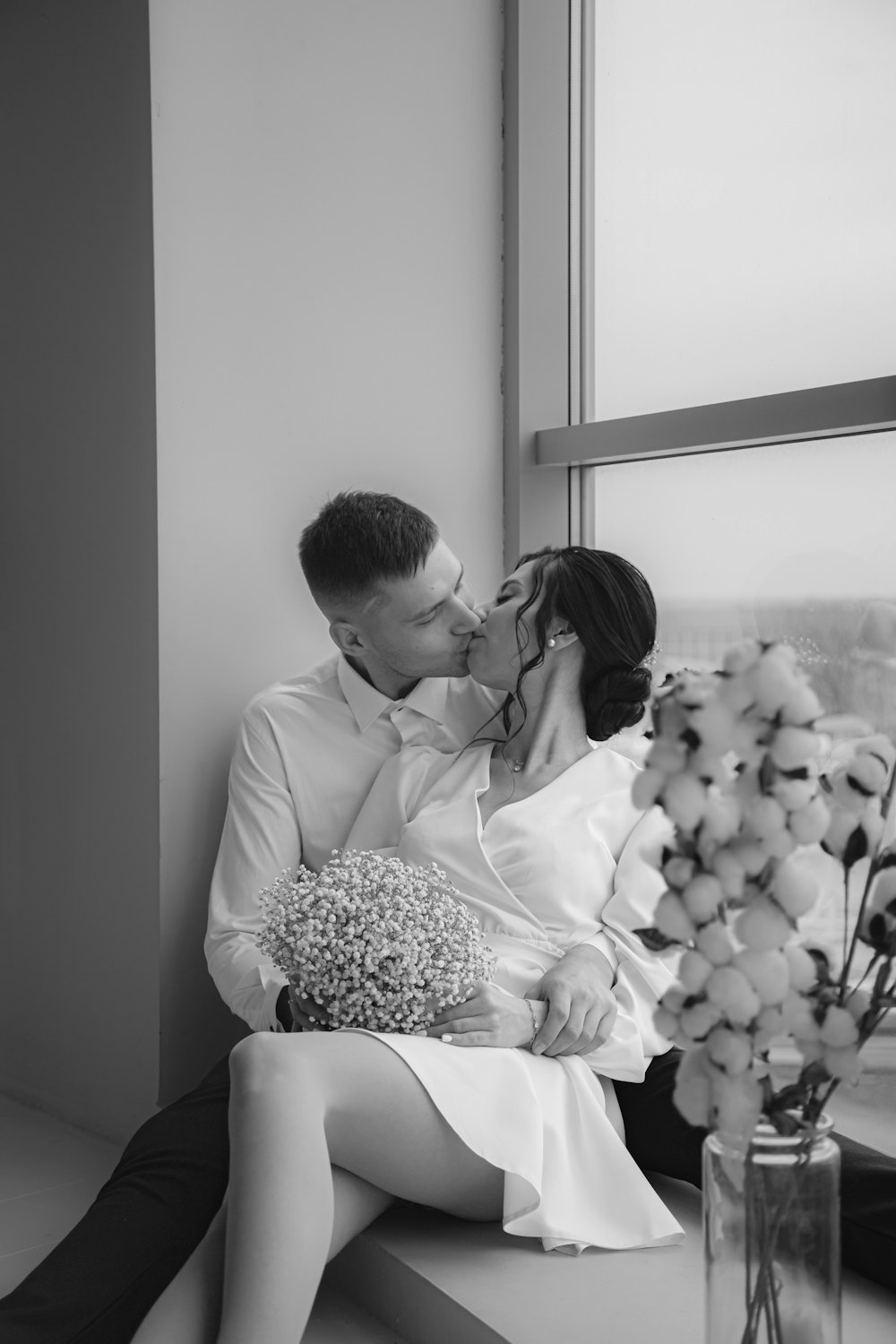 a man and a woman kissing in front of a window