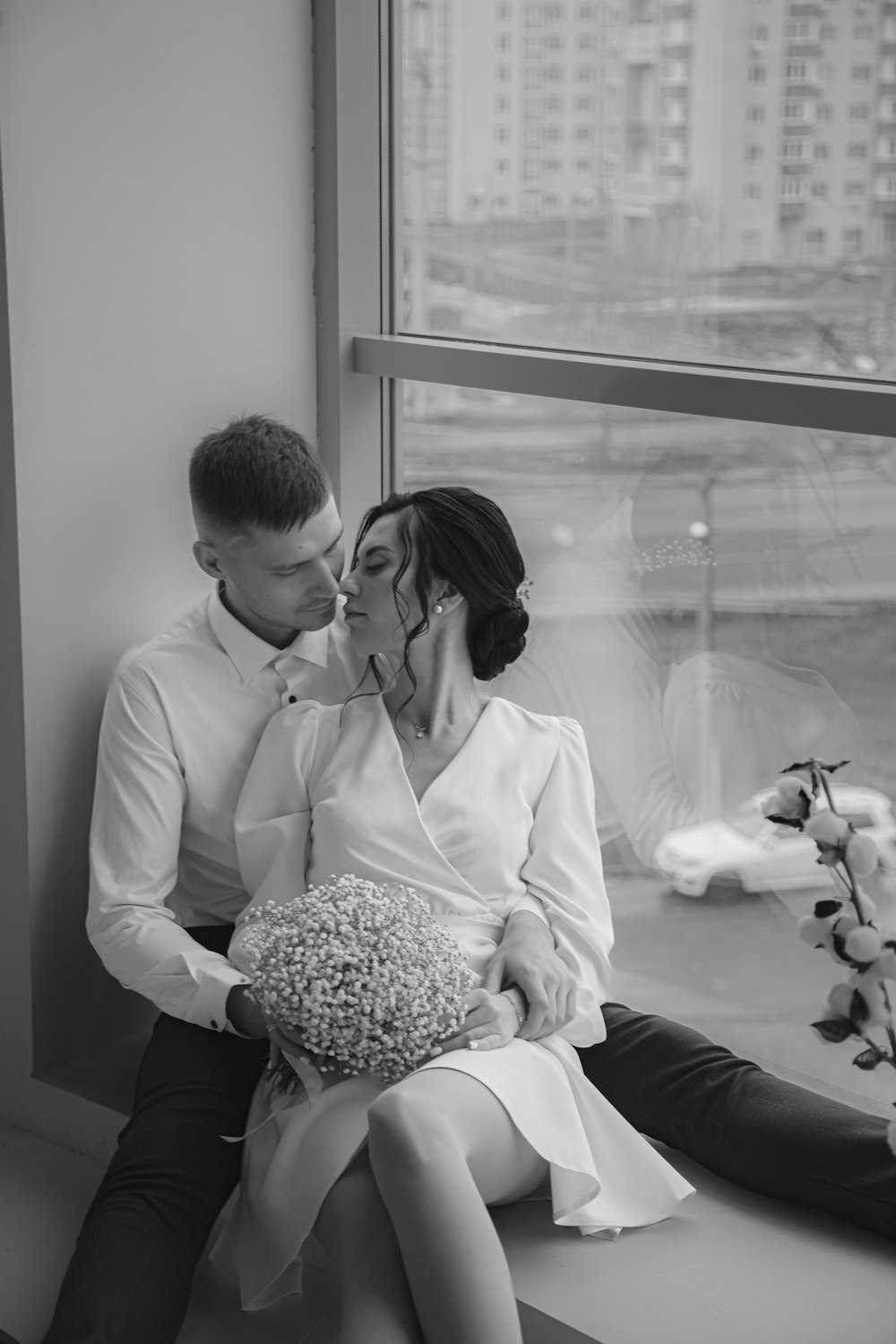 a man and woman sitting next to each other on a window sill