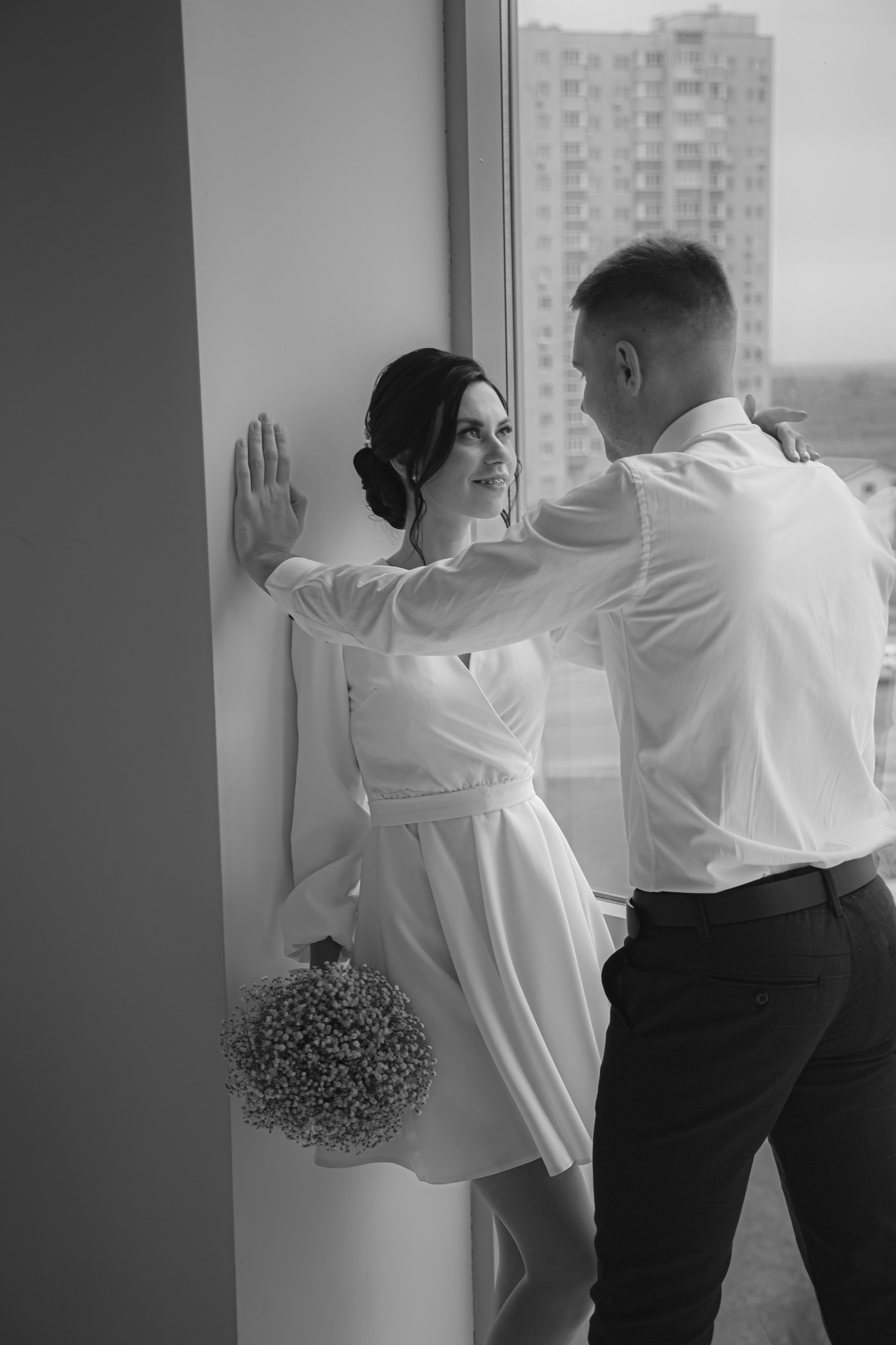 a man and woman standing next to each other near a window