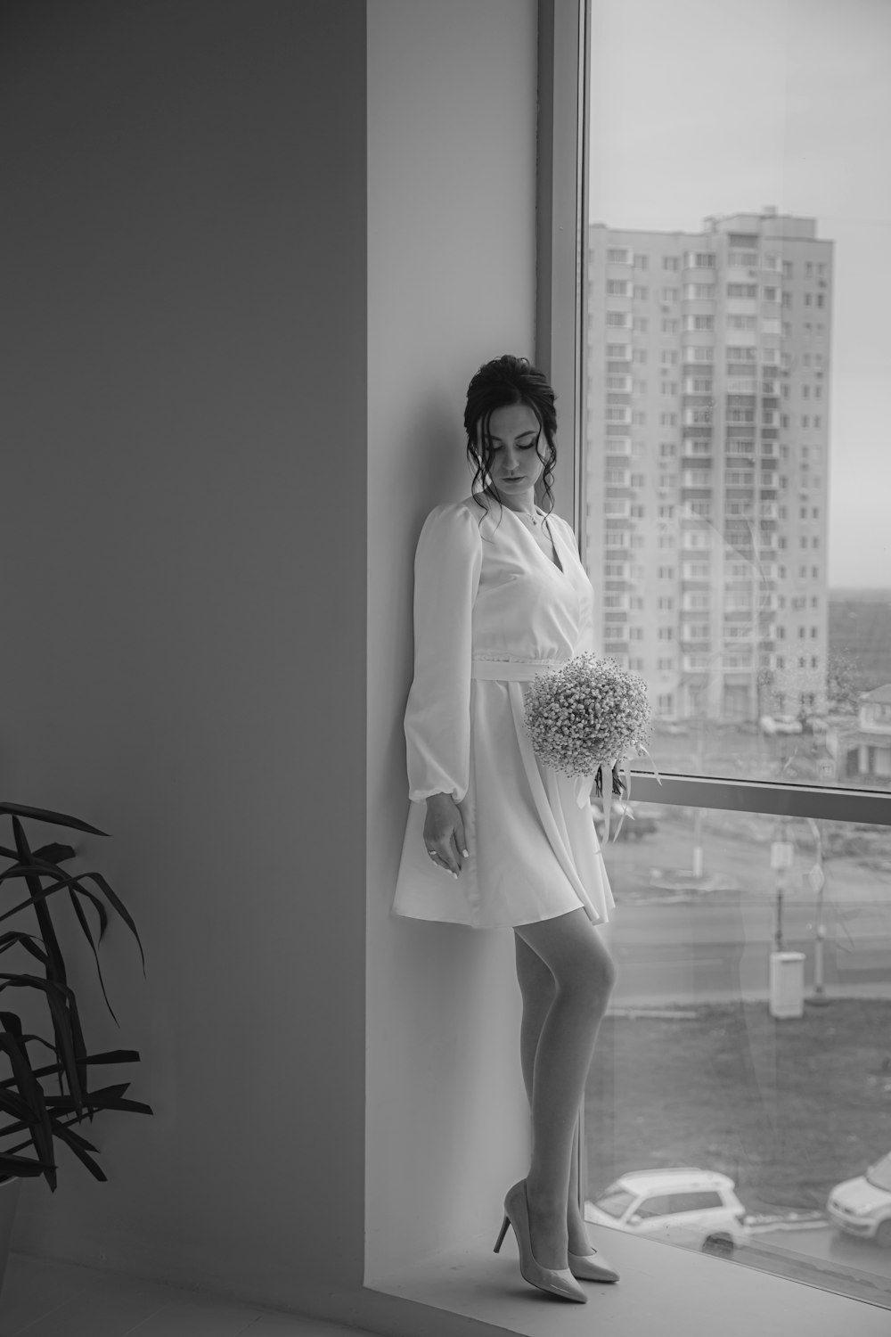 a woman standing next to a window holding a bouquet of flowers