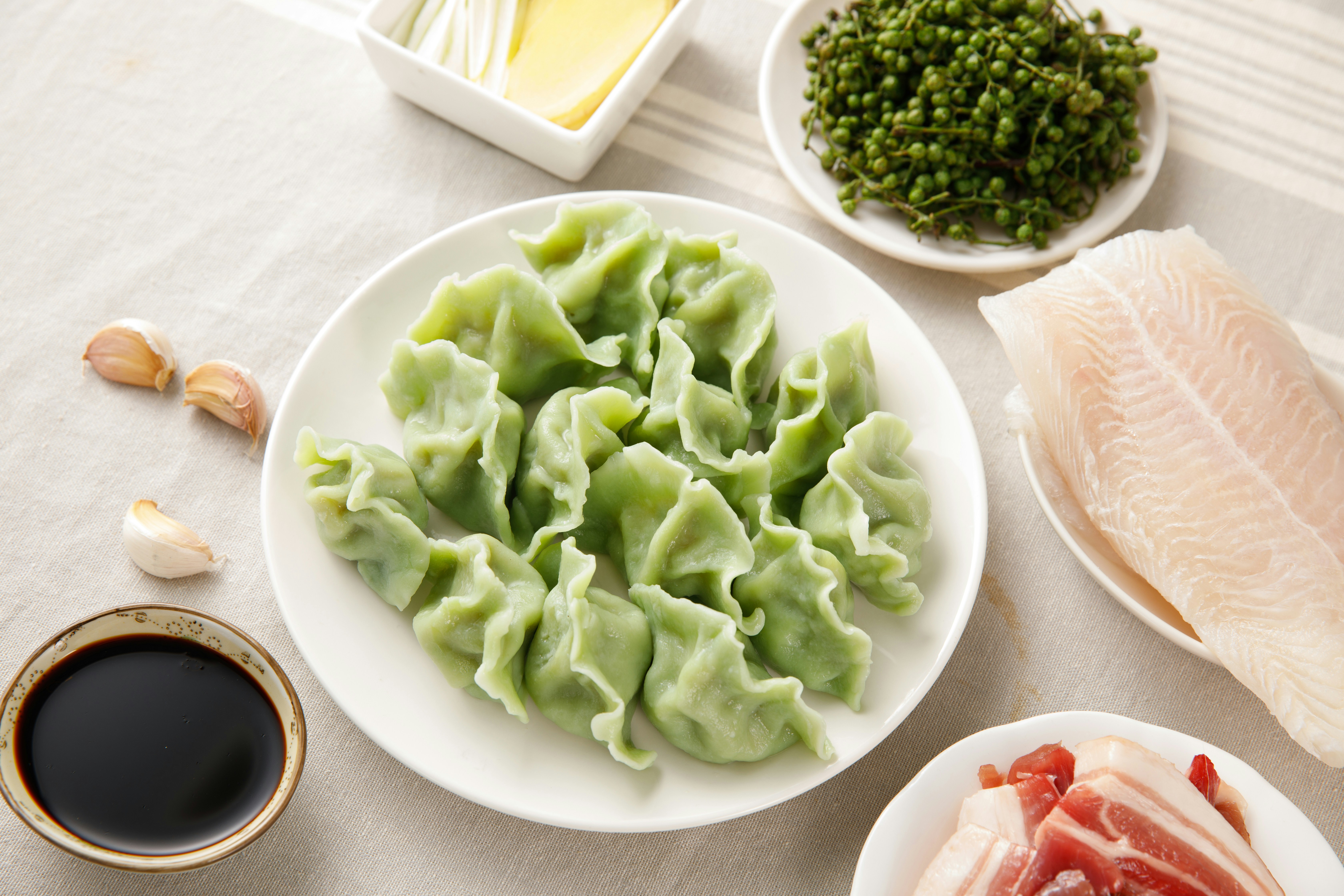 Green dumplings on a plate with soy sauce and garlic