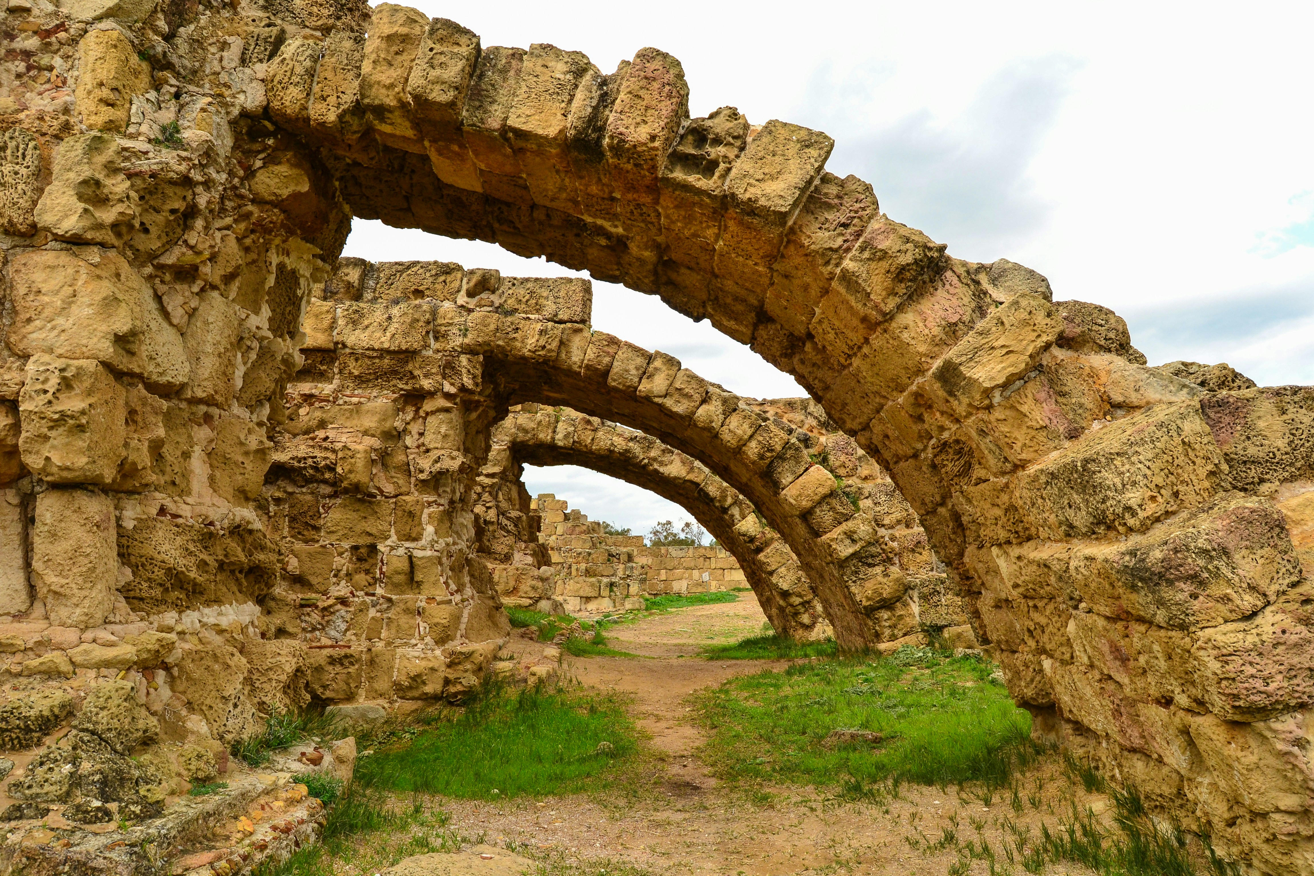 a stone arch in the middle of a dirt road