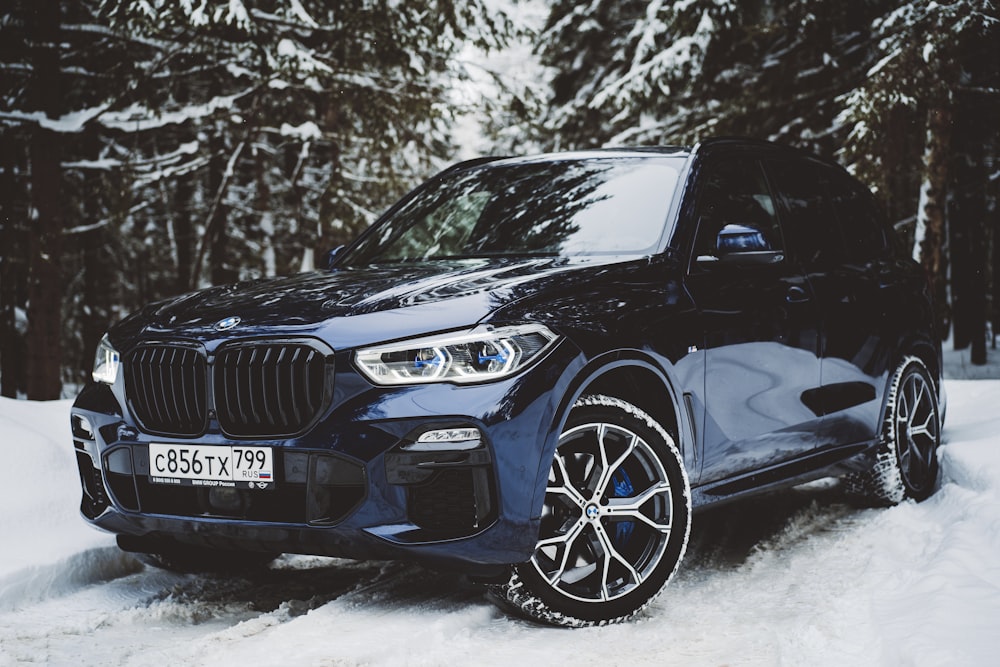 a blue bmw suv parked in the snow